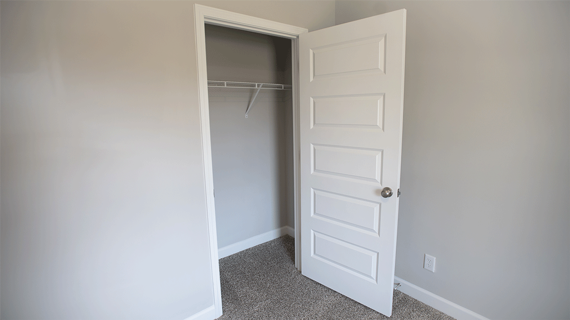 Bright guest room featuring plush carpet and a well sized closet.
