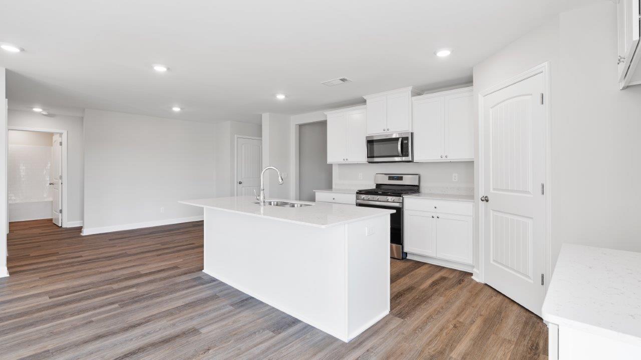 luxury vinyl plank flooring in kitchen with stainless steel appliances and Quartz countertops with soft close cabinets
