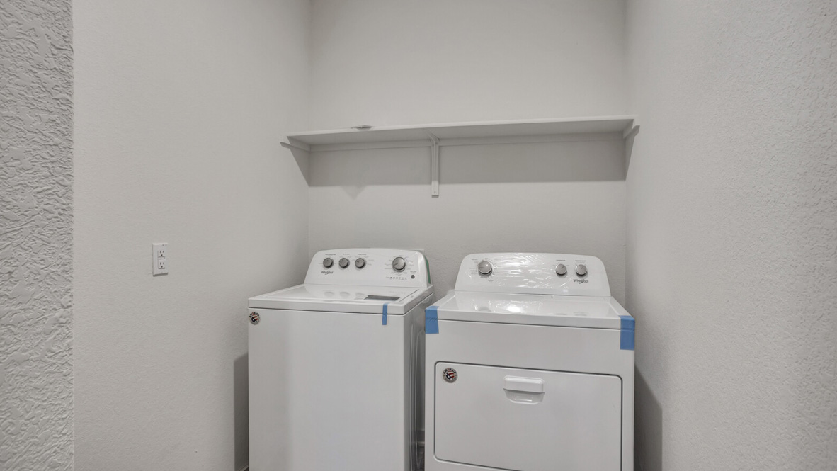 Laundry with a shelf above appliances.
