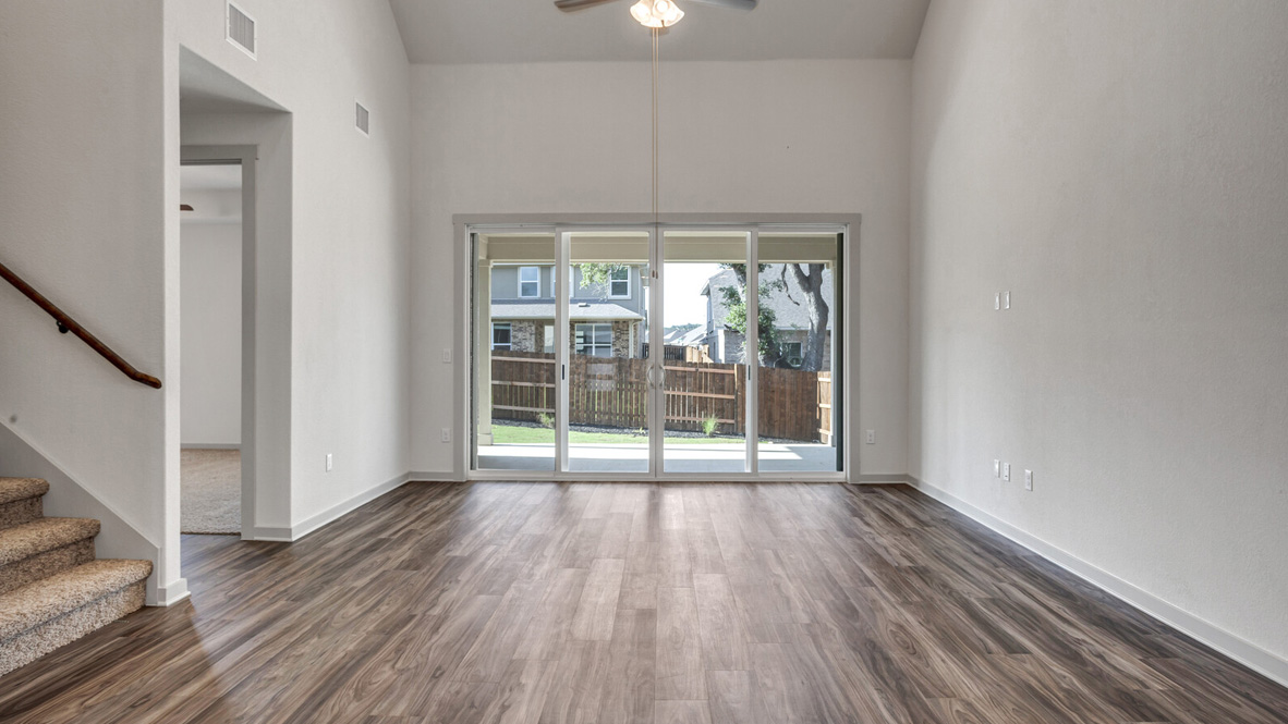 Living area with brown flooring, white walls, and large windows.