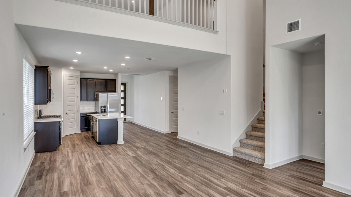 Living area with brown flooring, white walls, and a staircase.