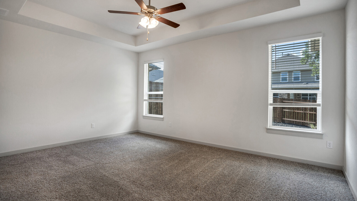 Bedroom with brown carpet, white walls, and windows.