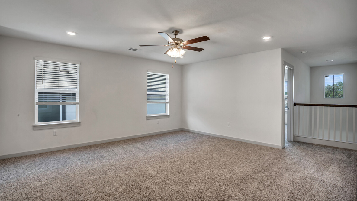 Loft with brown carpet, white walls, and windows.