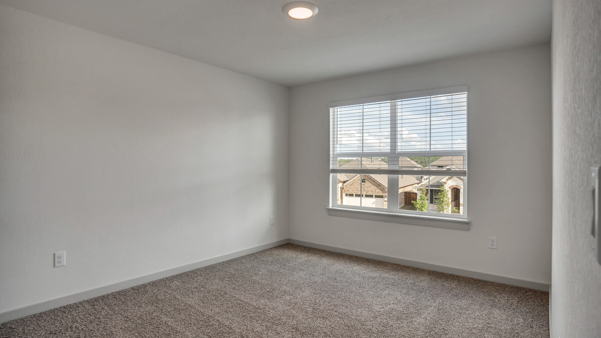 Bedroom with brown carpet, white walls, and a window.