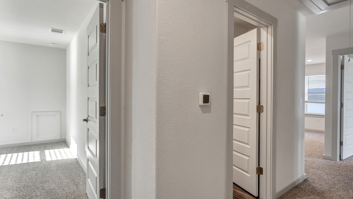 Hallway with carpet and white walls leading to bedrooms.