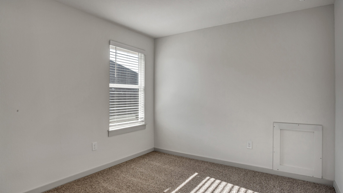 Bedroom with brown carpet, white walls, and a window.