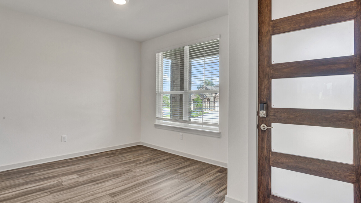 Entry way with room featuring brown flooring, white walls, and a large window.