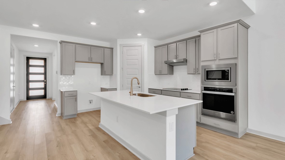 View from family room into kitchen with hard surface countertops and dark wood upper and lower cabinets at Thunder Rock
