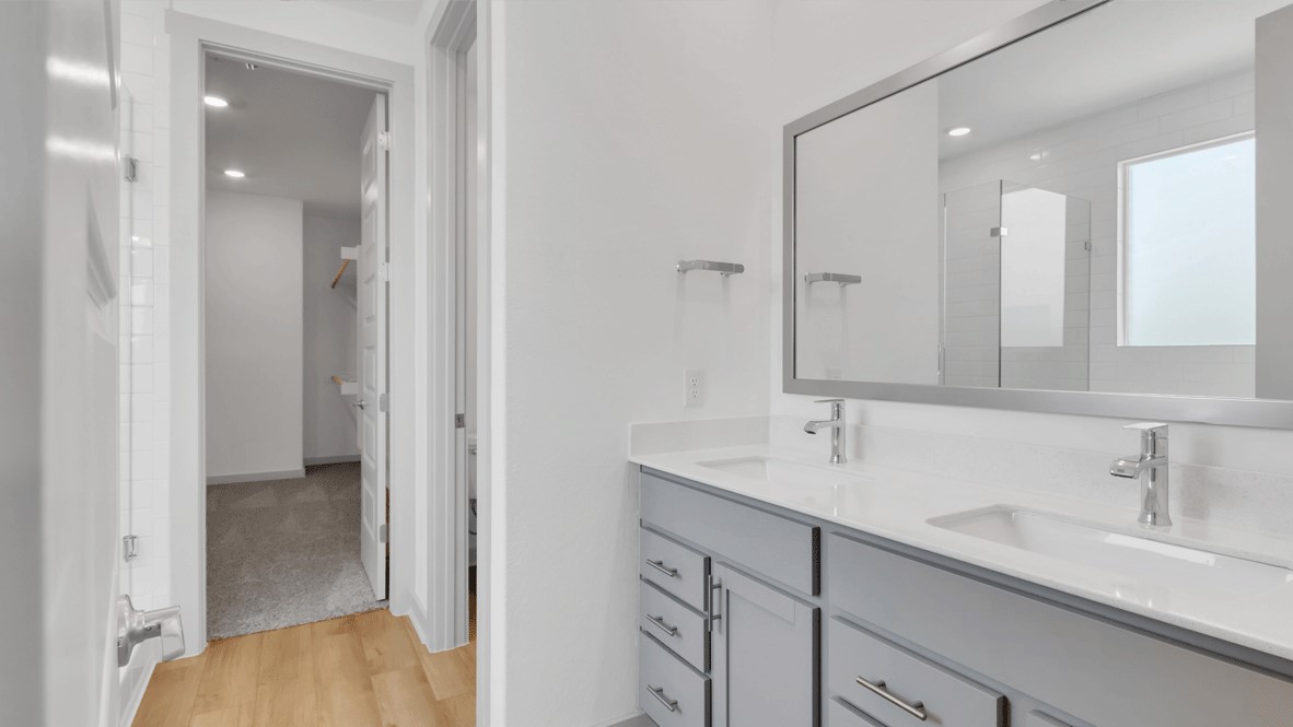 Secondary bath with built-in tub and shower combo, vanity lighting, and framed mirror in Thunder Rock