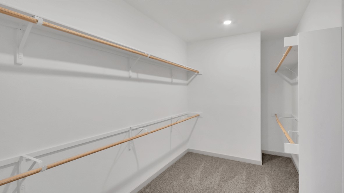 Walk-in closet with built-in shelving and carpet flooring off primary bathroom in Thunder Rock