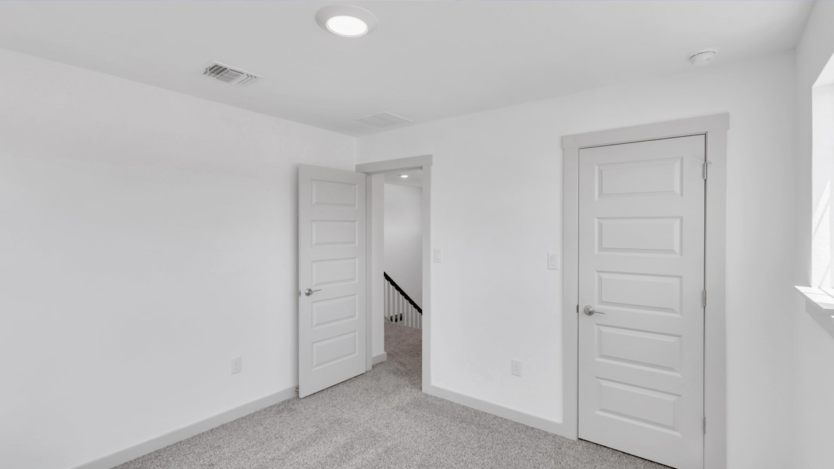 New Home primary bedroom features wide wall space for furniture placement and access to a private ensuite bathroom, walk-in