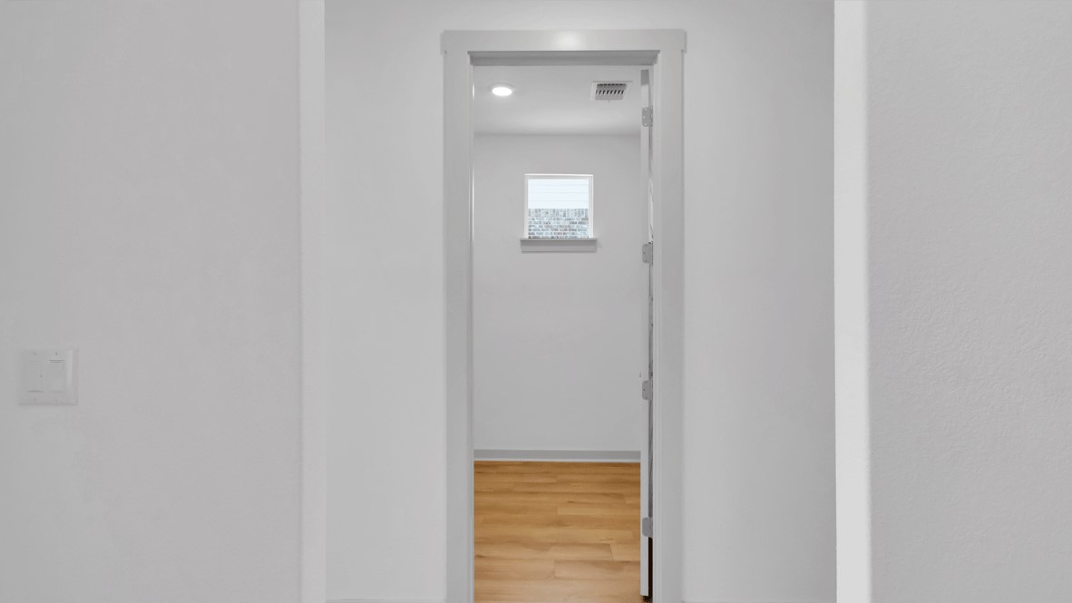 Functional hall shows clean wall design, LED fixtures, and seamless flooring continuing into the heart of the home looking back at single front door