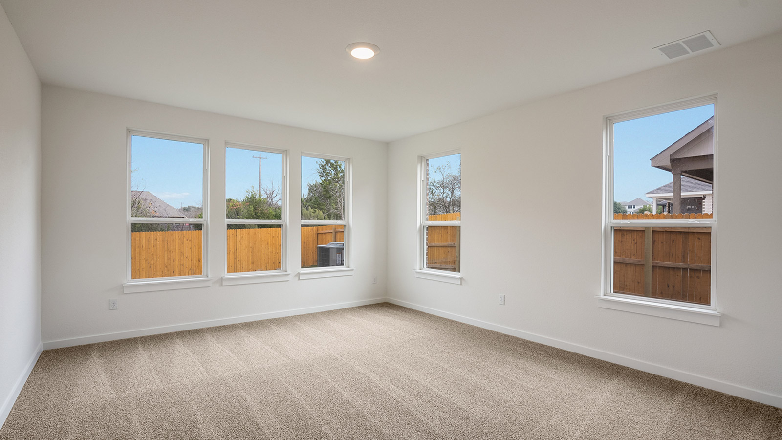 Large main bedroom, bedroom 1. with carpeted flooring and five wiindows.