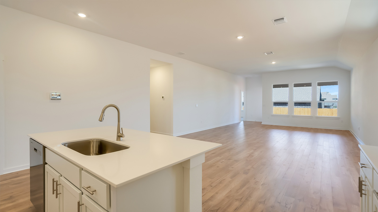 View over the kitchen island highlighting sink, prep zones, and connection to dining and living rooms Rosenbusch Ranch