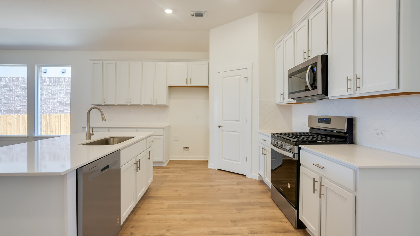 Side kitchen view highlighting pantry access, cabinetry, and functional prep layout