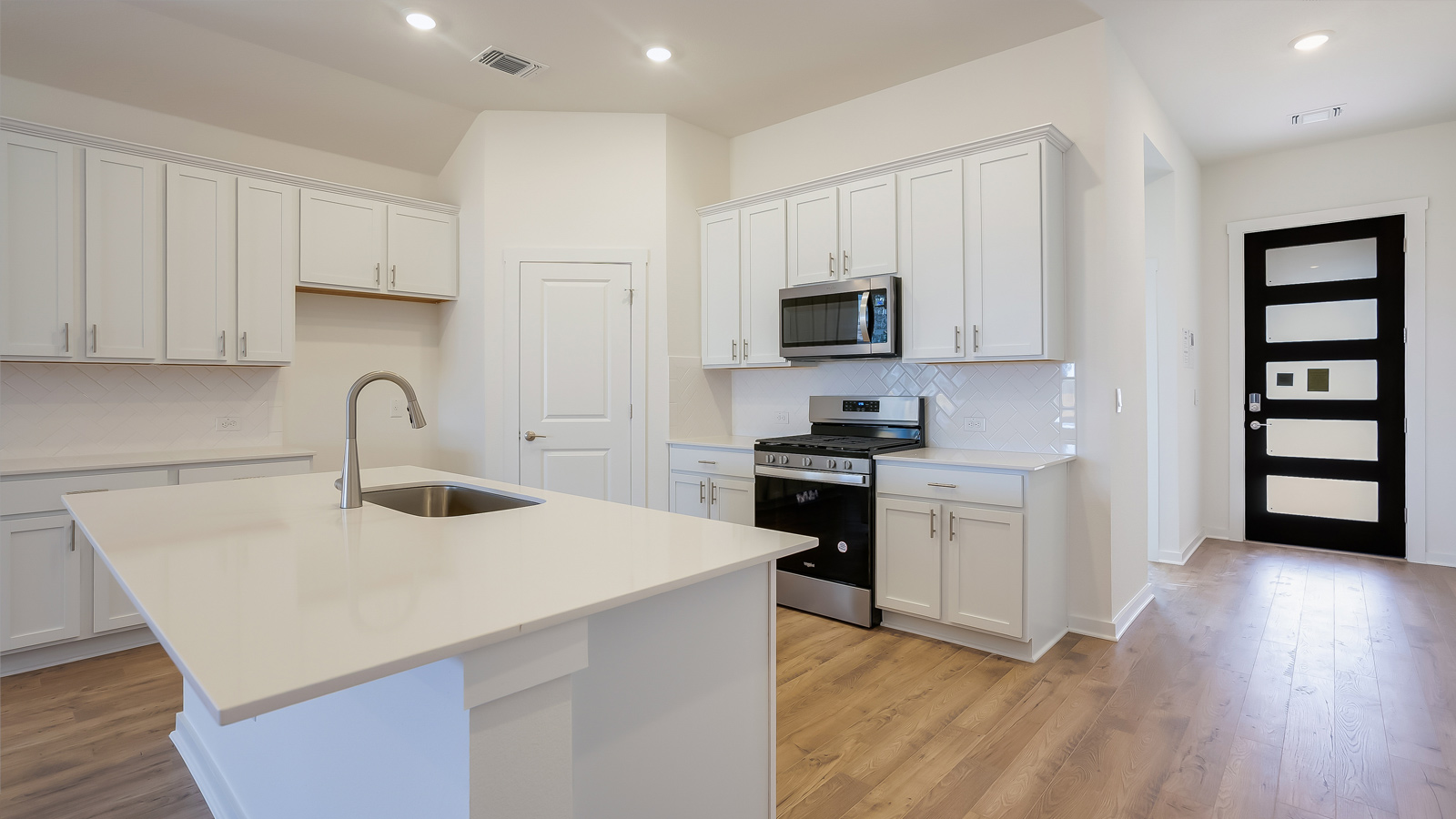 Central kitchen island with sink, seating, pantry, and cabinets anchoring the home’s main living space Rosenbusch Ranch