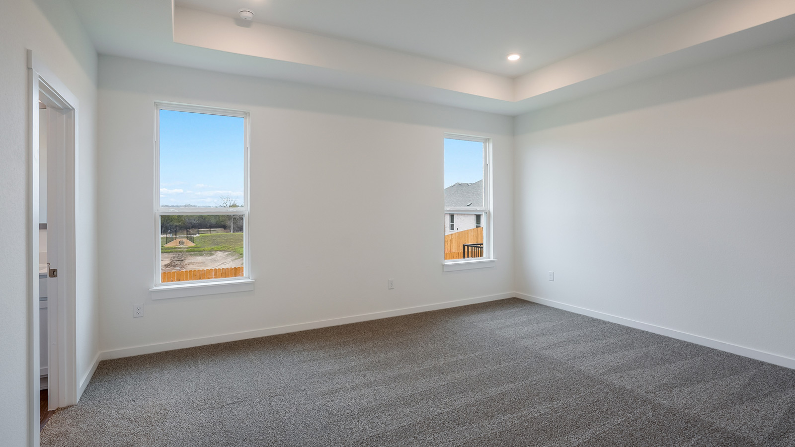 The main bedroom, bedroom 1, with carpeted floors and two windows.