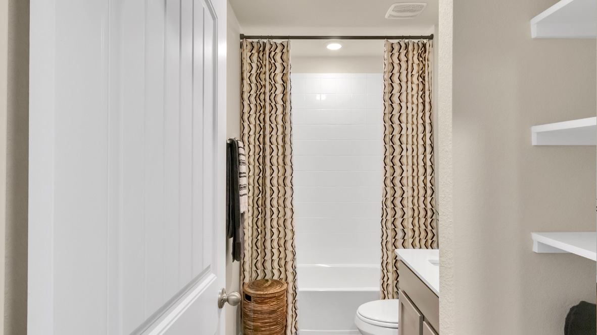 Family bathroom with stylish vanity, mirror, polished fixtures, cabinets, tub-shower combo in Rosenbusch Ranch
