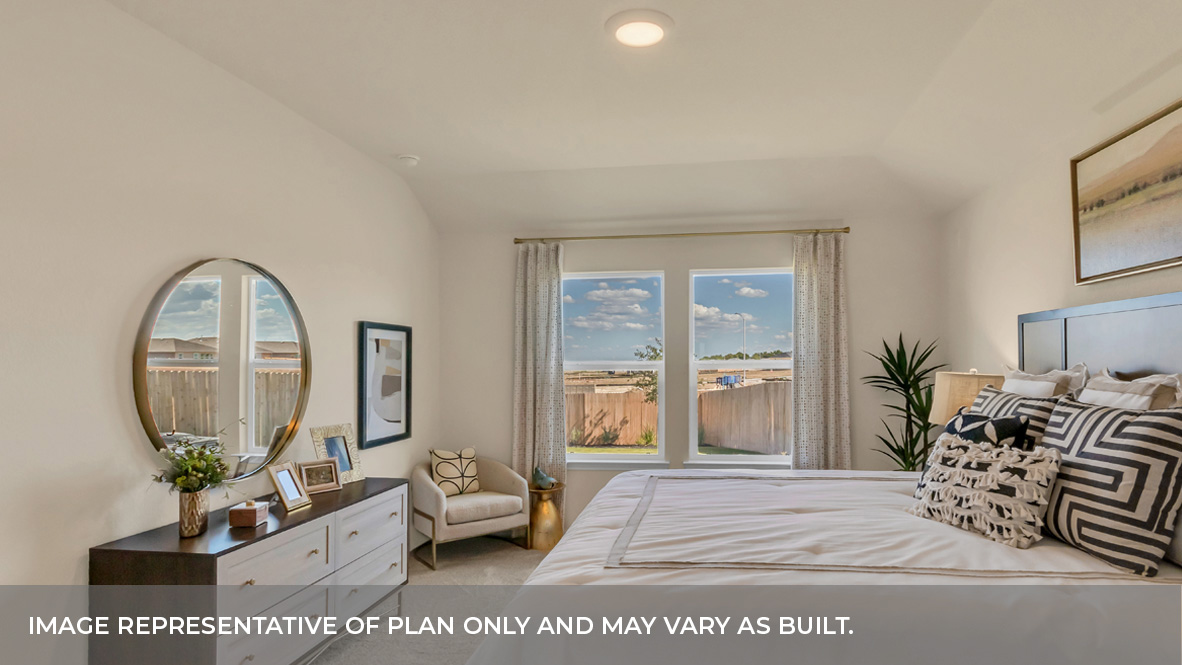 Primary bedroom with carpeted floors, two large windows, and trey ceilings.