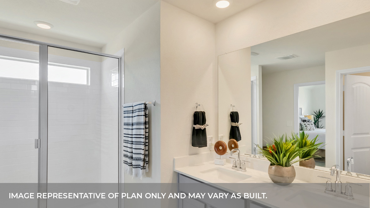 Primary bathroom with white tile walk-in shower, bright light fixtures, and with built in shelves.