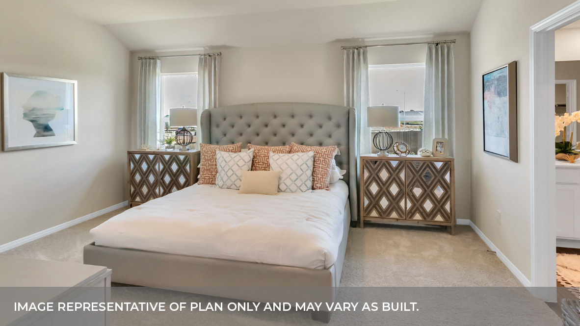 Primary bedroom with carpeted floors, two large windows, and trey ceilings.