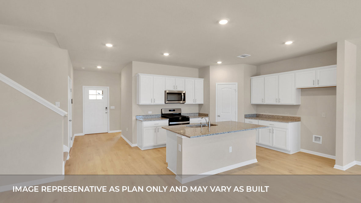 Kitchen area with stairs to the left and the front entrance foyer hall in the back.