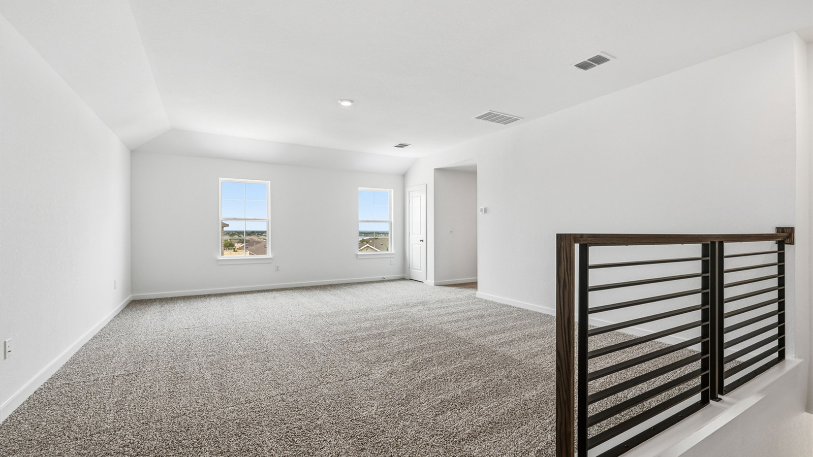 Upstairs game room with staircase and railing.