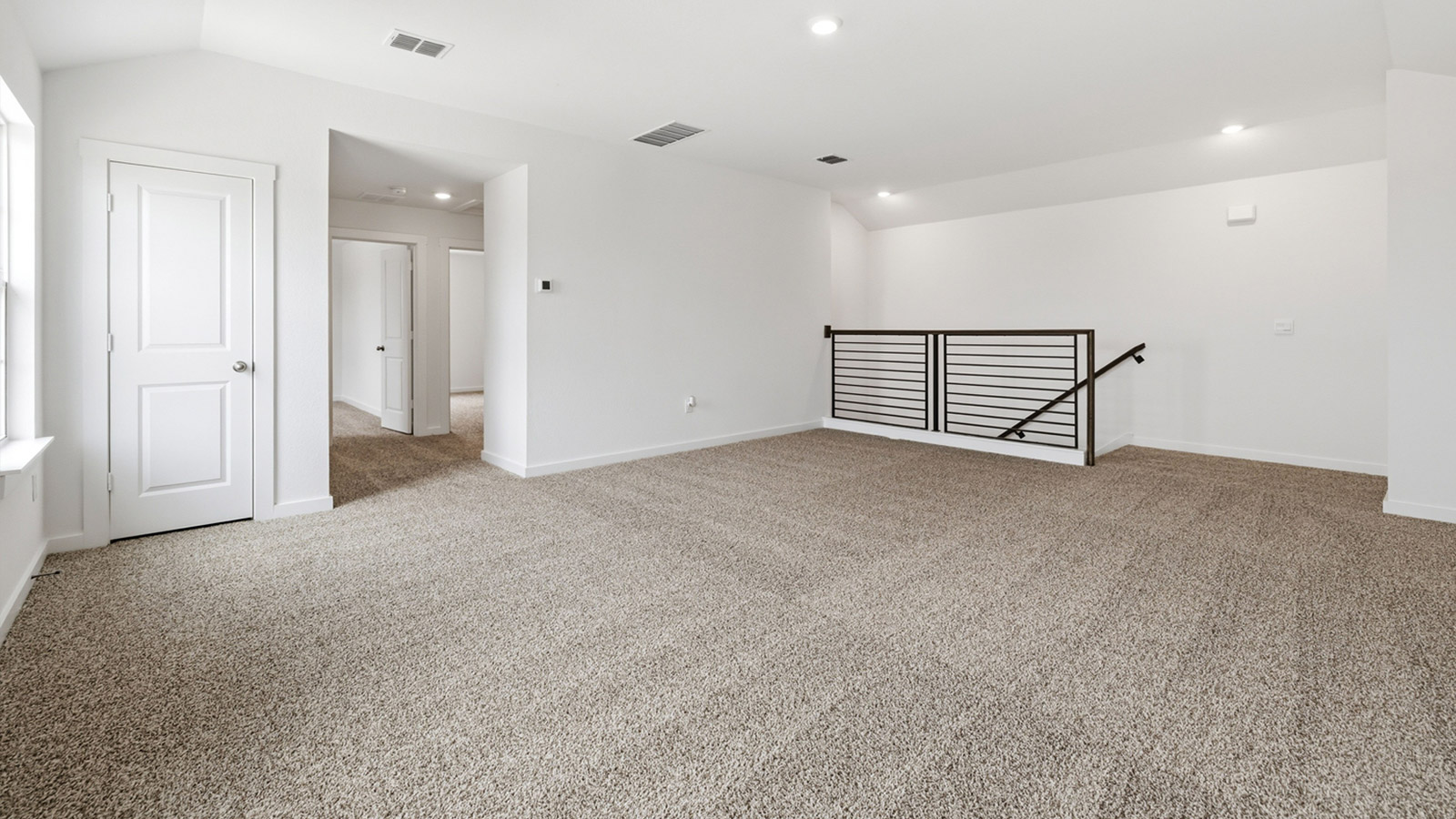 Spacious upstairs game room with carpeted flooring.