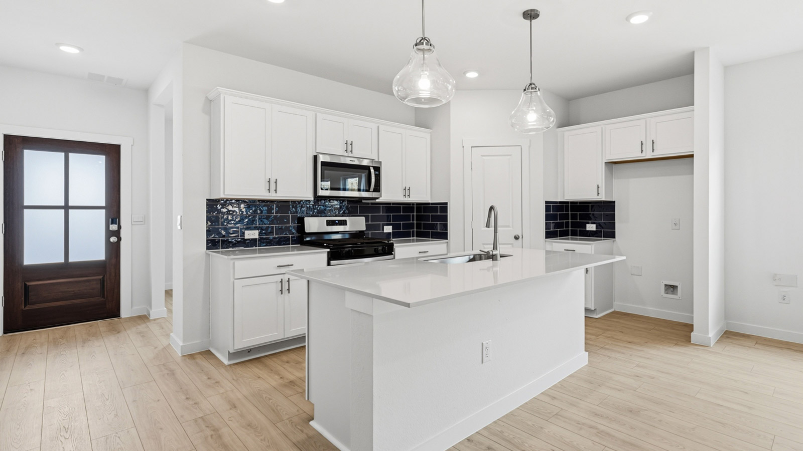 Beautiful kitchen with navy blue backsplash and white cabinets with hardware.