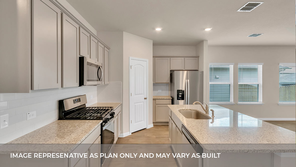 Side view of the kitchen area with light tan granite countertops, large island, Light gray cabinets, and stainless steel appliances with pantry in the corner.