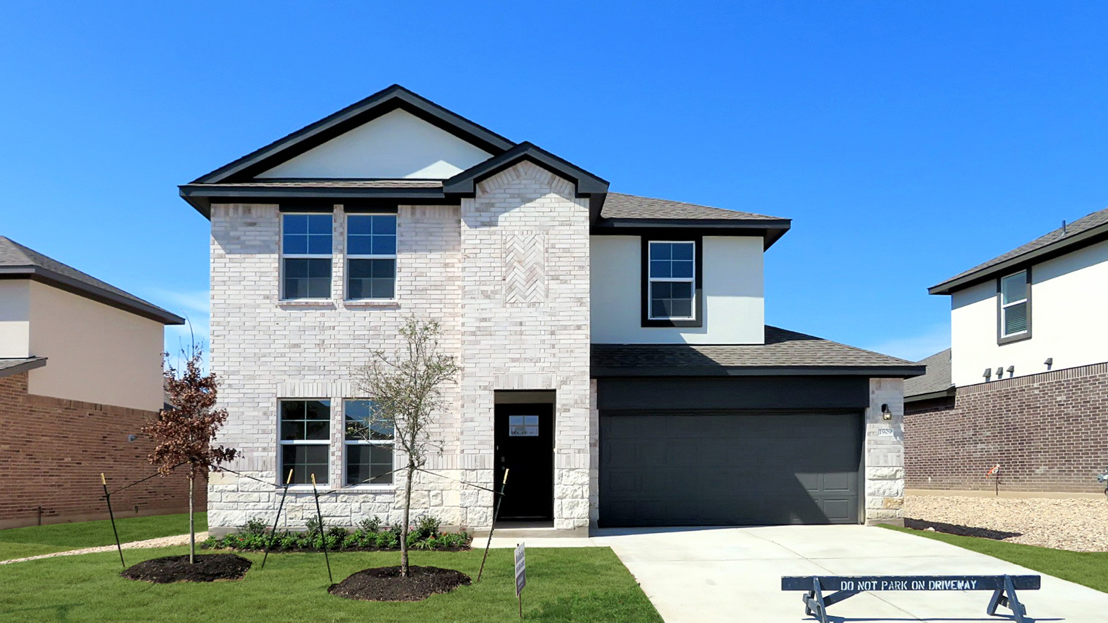 Two story home with white brick and a two car garage.