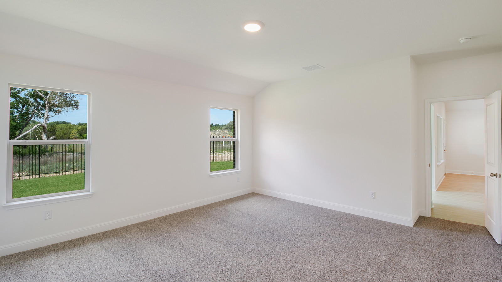 bedroom with beige carpet, white walls and 2 windows