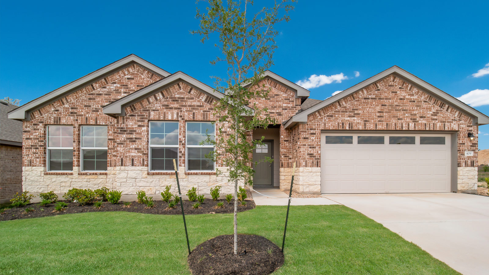Front exterior of the Holden floorplan home featuring brick and stone accents, and a 2 car garage