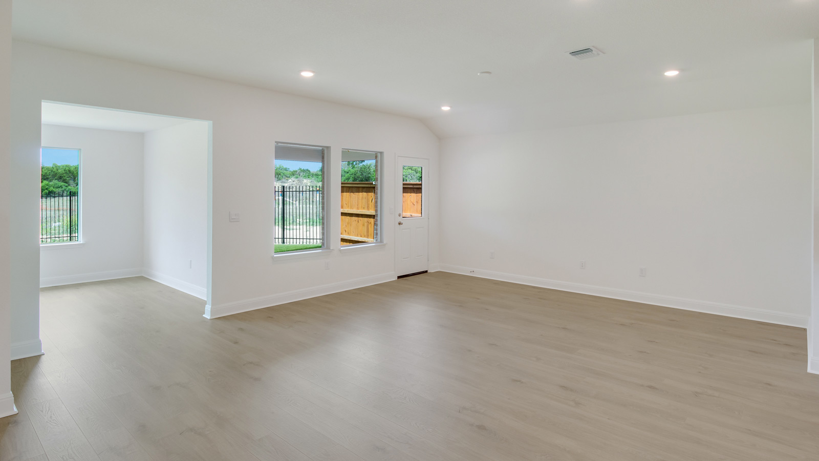 spacious living area featuring light brown floors and white walls