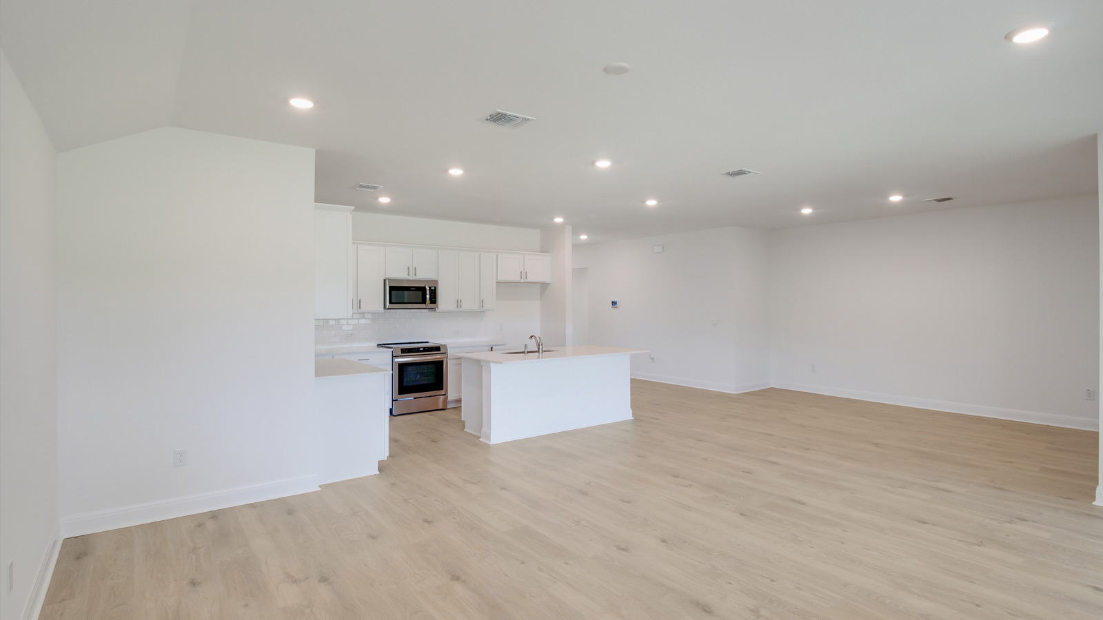 spacious living area featuring light brown floors and white walls