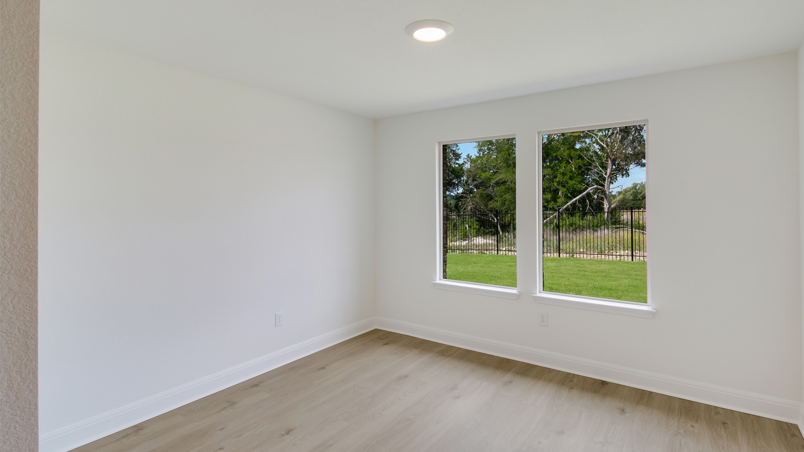 dining area with light brown flooring, white walls and 2 windows overlooking the backyard