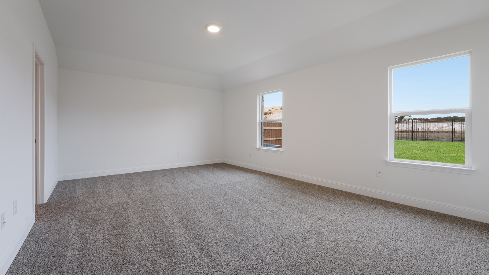 The main bedroom, bedroom 1, with carpeted floors and two windows.