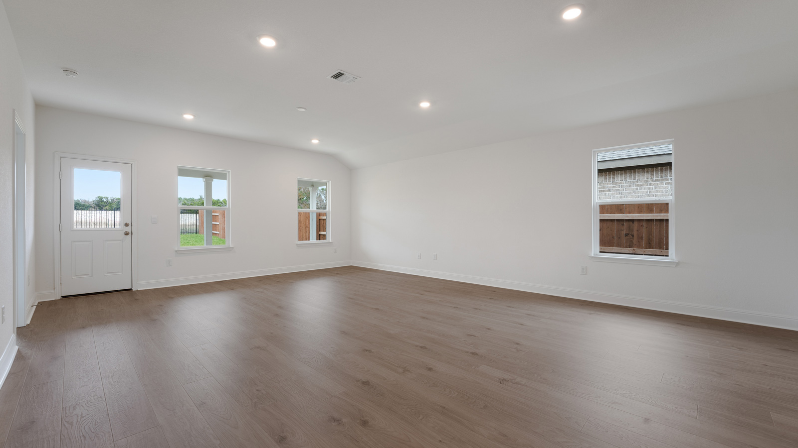 Vast living area with laminated wood flooring.