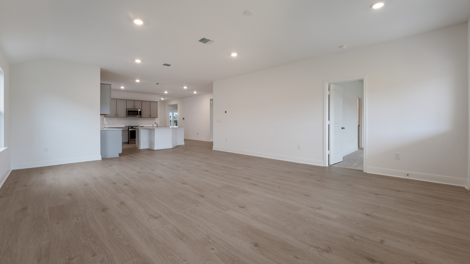 Vast living area with laminated wood flooring.