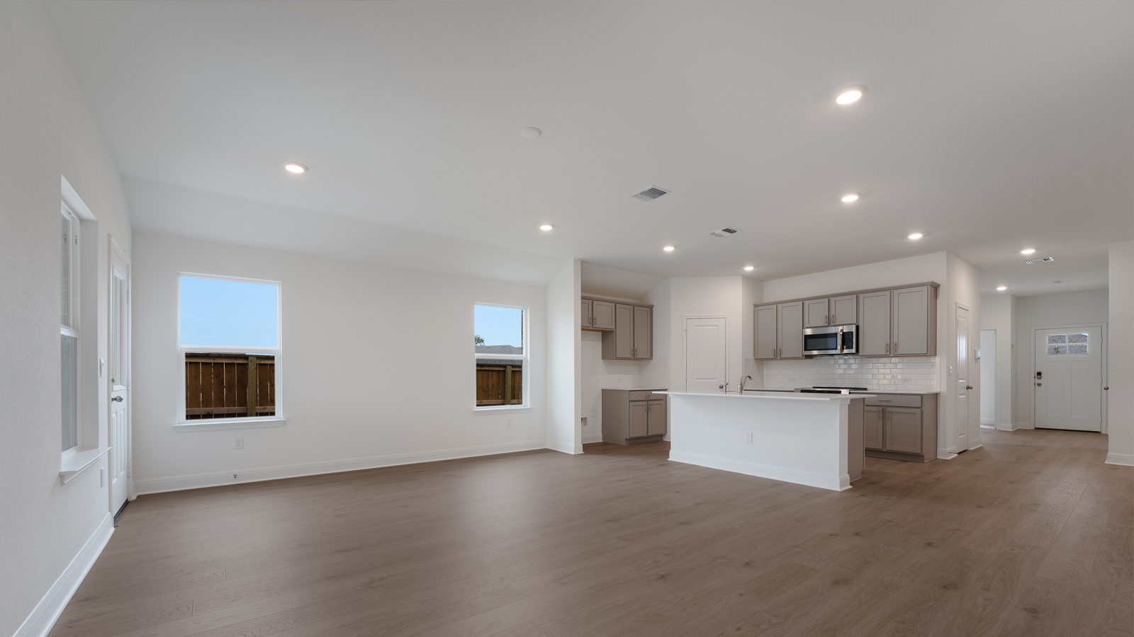 Open living area and kitchen with windows that let in natural light.