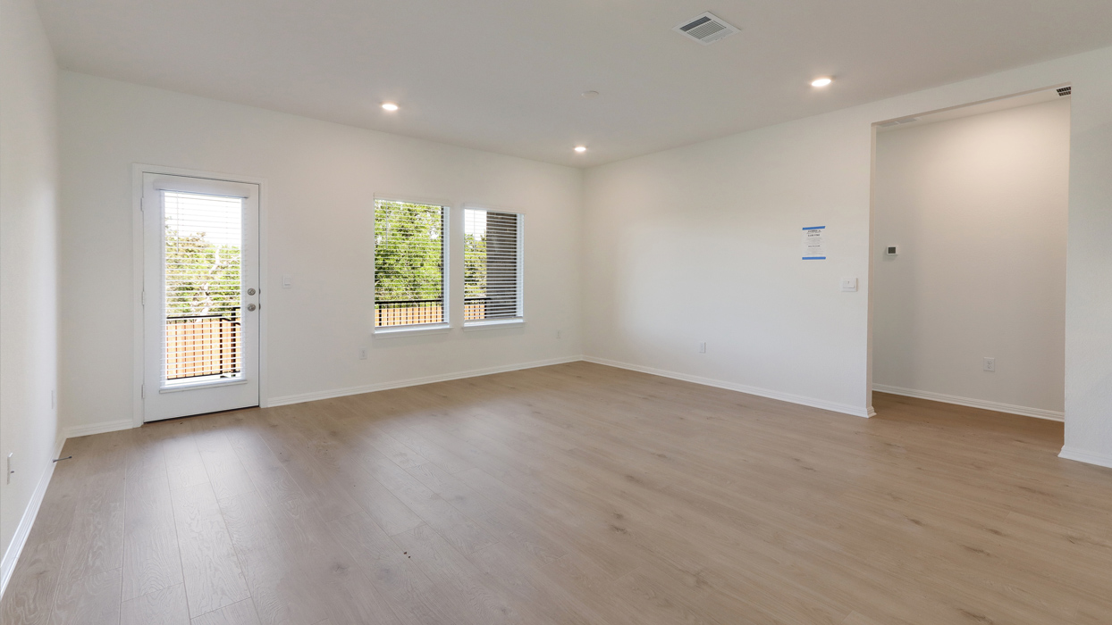 Living room with a large window for natural lighting and a door for access to backyard.