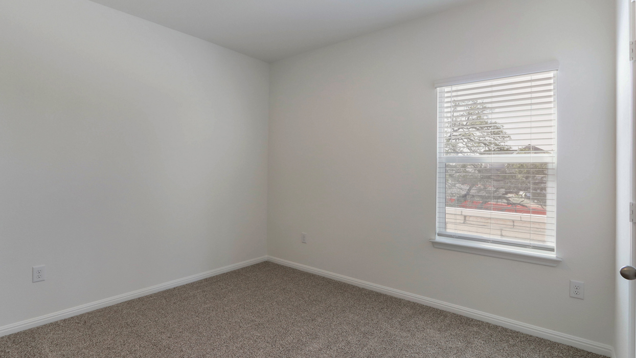 Bedroom with single window and carpeted floors.