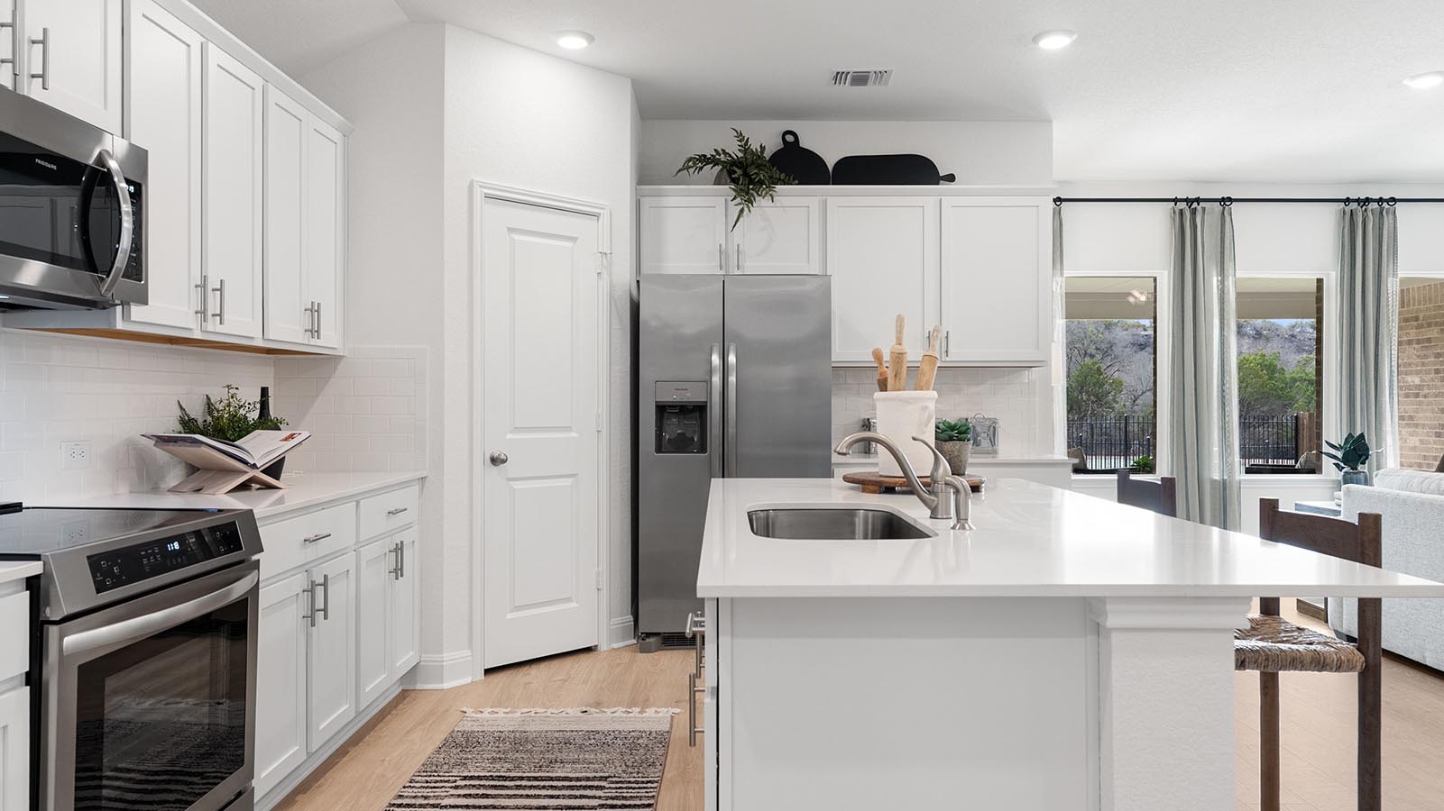 kitchen with white cabinets and island with sink. granite counterrops and stainless steel appliances