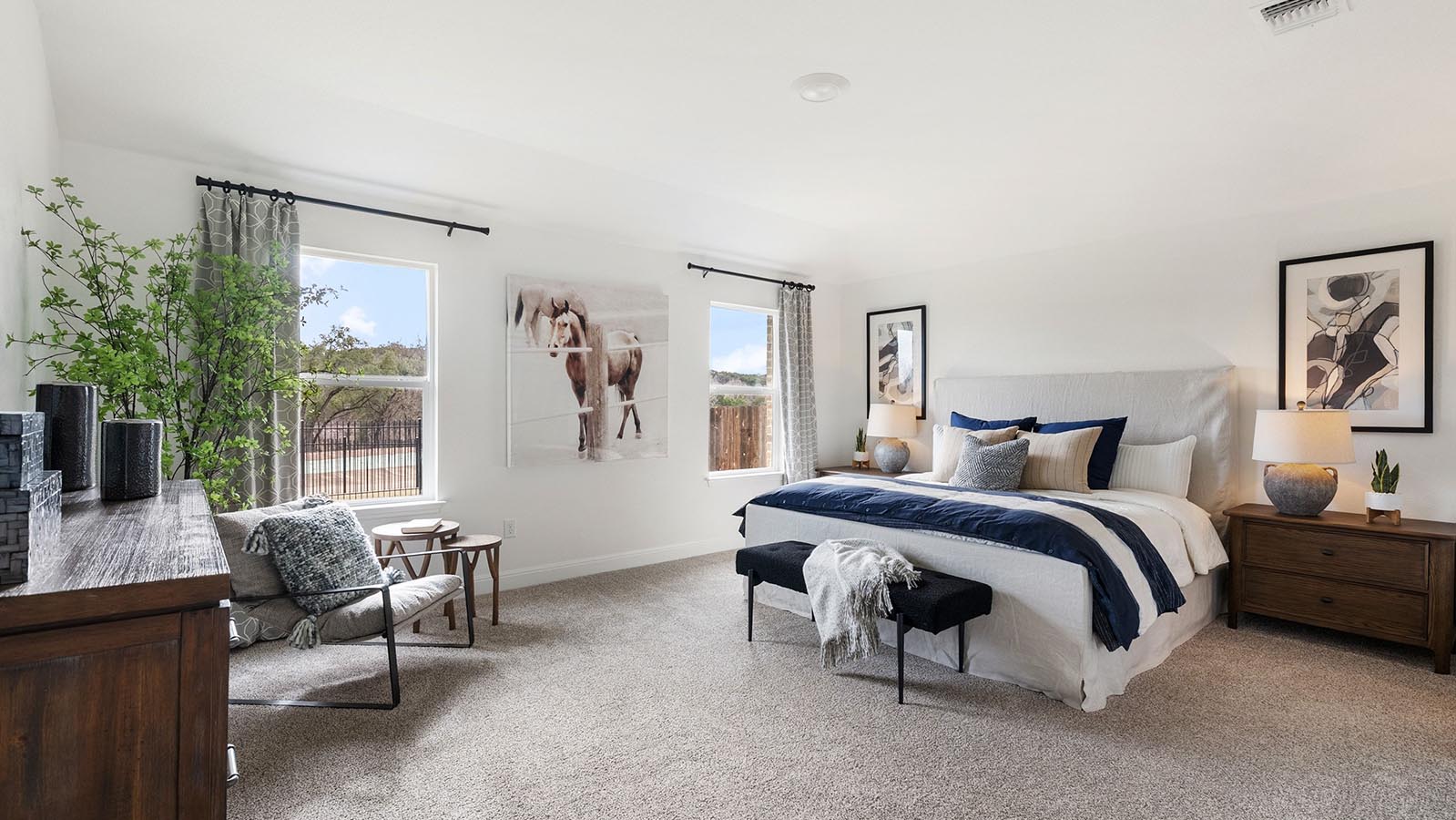 Primary bedroom with carpet and two windows with kind bed