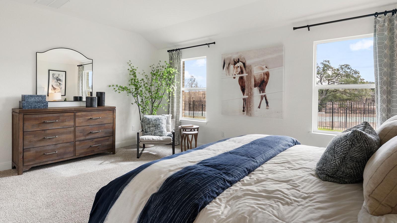 Primary bedroom with carpet and two windows with kind bed