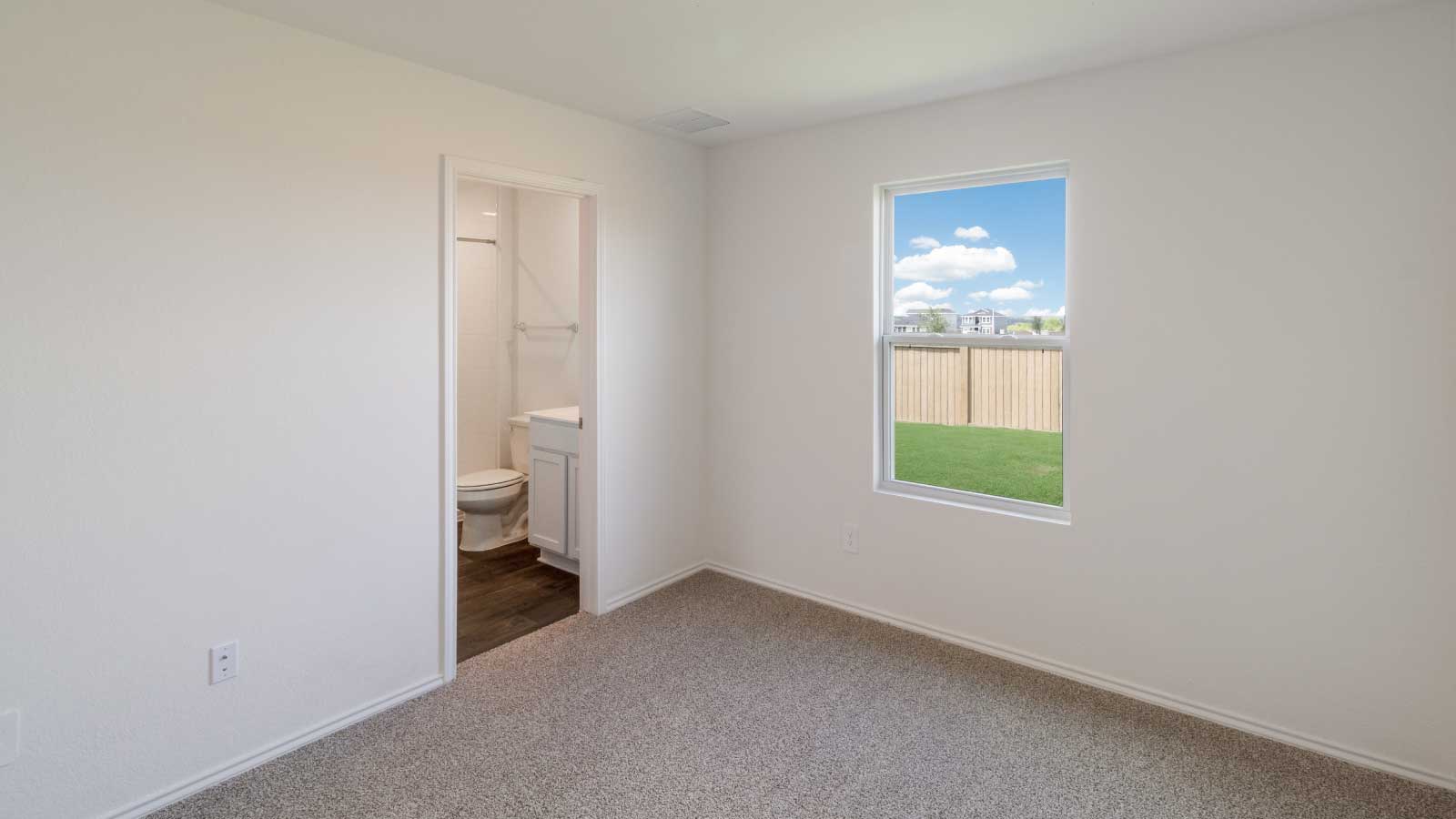 Bedroom with brown carpet, white walls, and a window.