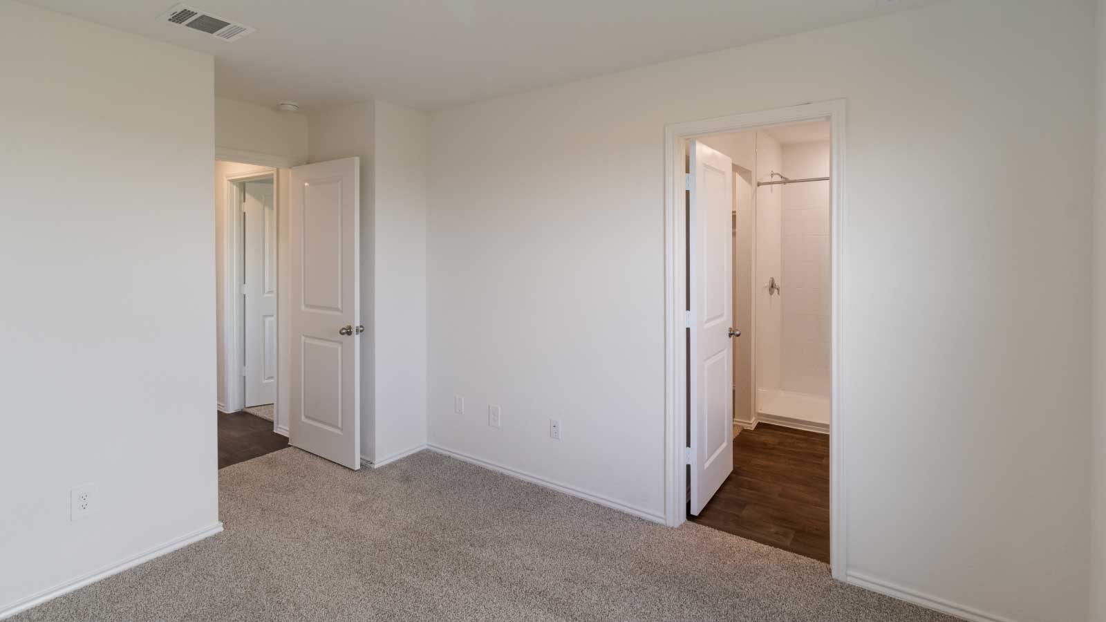 Bedroom with brown carpet, white walls, and a bathroom connected.
