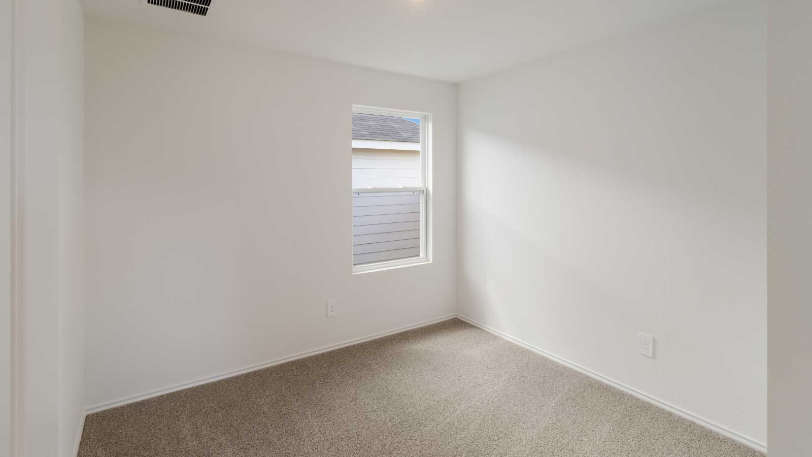 Bedroom with brown carpet, white walls, and a window.