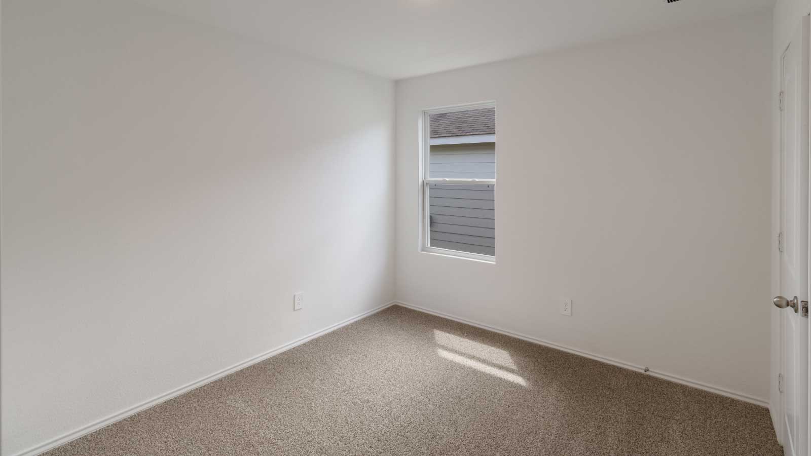 Bedroom with brown carpet, white walls, and a window.