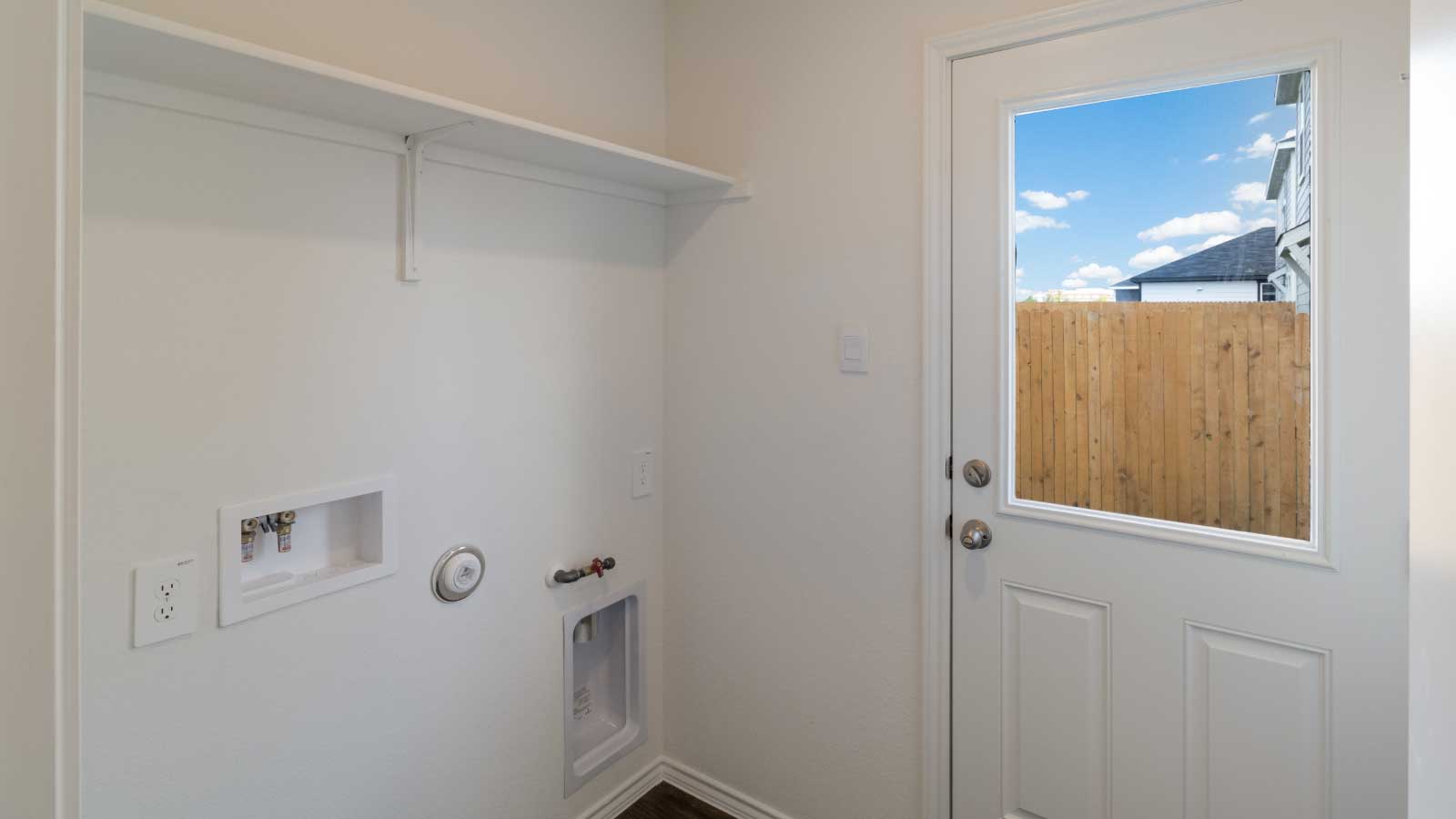 Laundry room with shelving and a door to the backyard.
